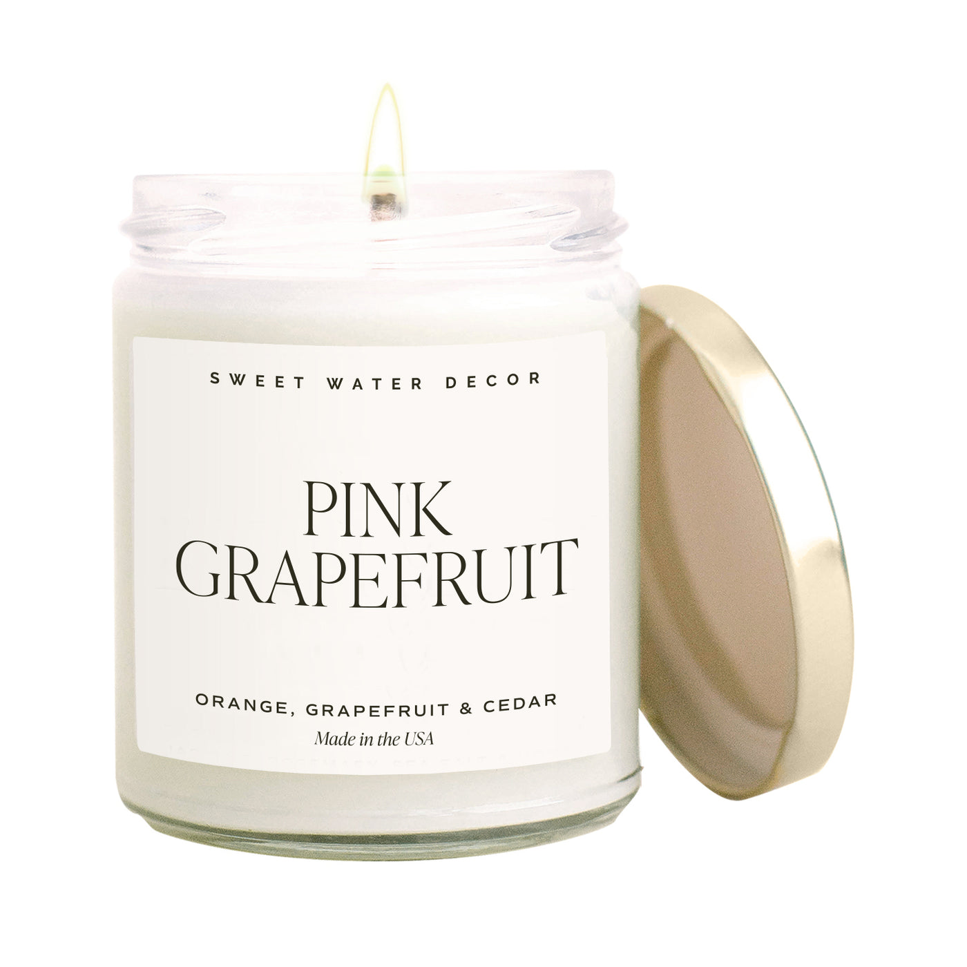 Clear Candle Jar with gold lid. Pink Grapefruit label and scent notes of orange, grapefruit, and cedar.